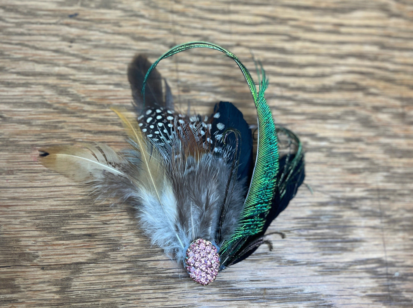 pink broach with peacock curled peacock feather 